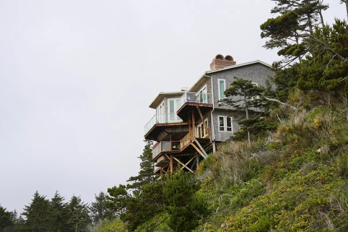 Hillside home with stacked elevated decks supported by tall timber posts and diagonal bracing