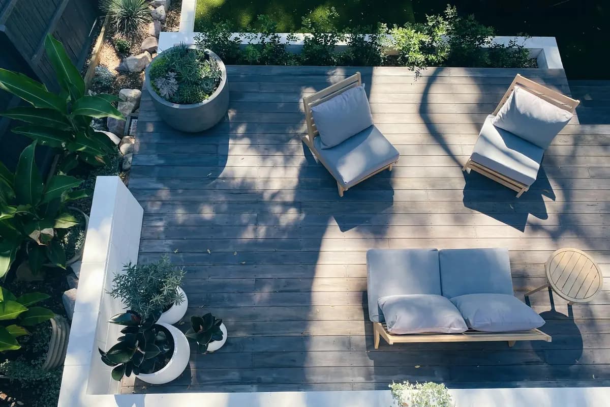 Overhead view of a large gray deck with lounge chairs and planter pots