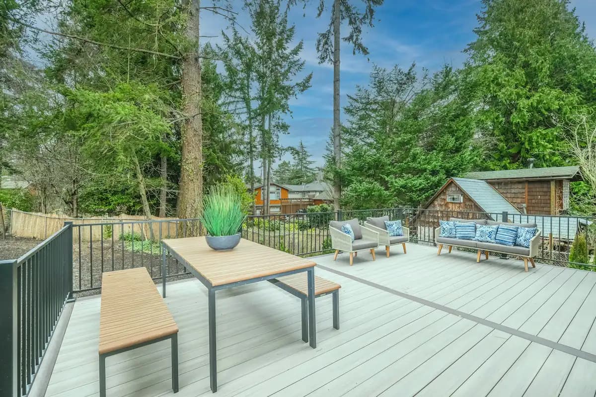 Spacious light-gray composite deck with black metal railing, dining and lounge seating