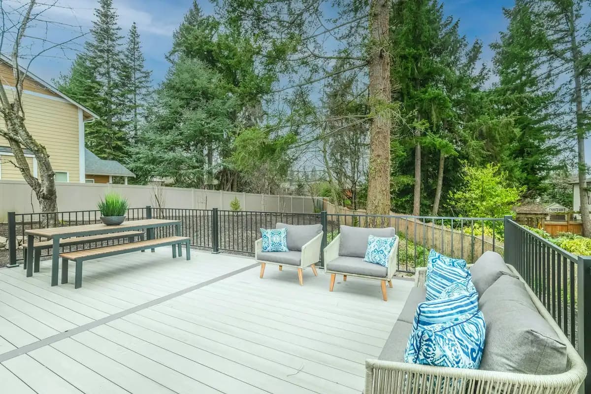 Ground-level light-gray composite deck with a picnic-style dining bench and outdoor sofas