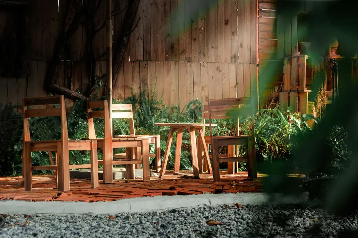 Two wooden chairs and a small side table on a ground-level deck-tile pad