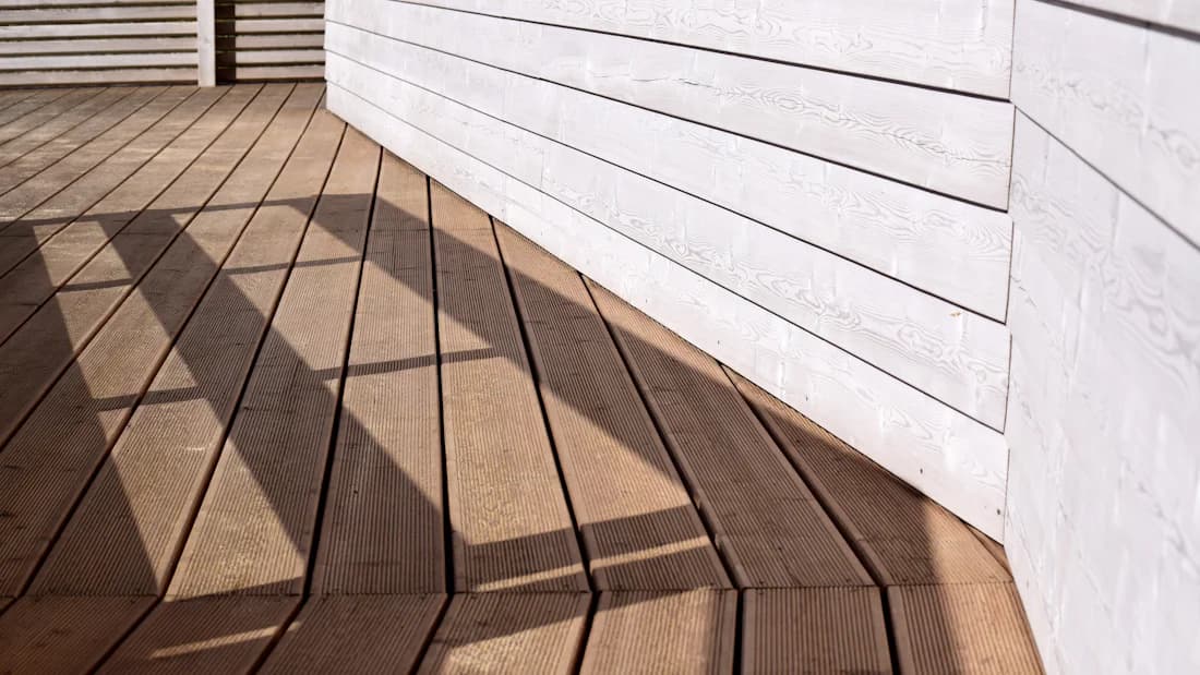 Deck boards laid in a diagonal pattern meeting a white wall