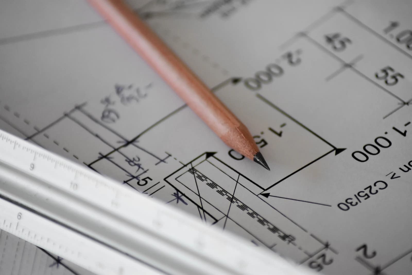 A pencil resting on a sheet of white paper with construction drawing lines