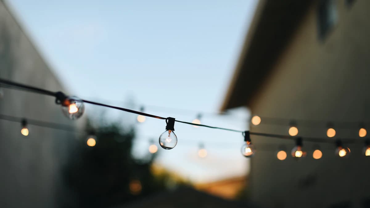 A backyard deck lit in the evening with warm outdoor lighting