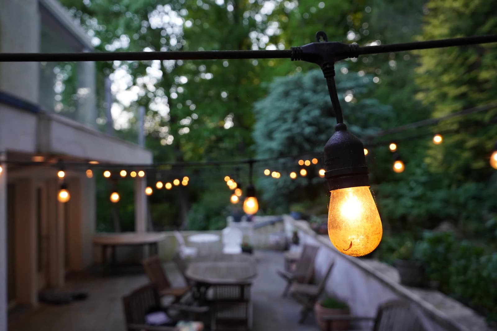 A fully lit backyard deck in the evening with a warm glow across railings and steps