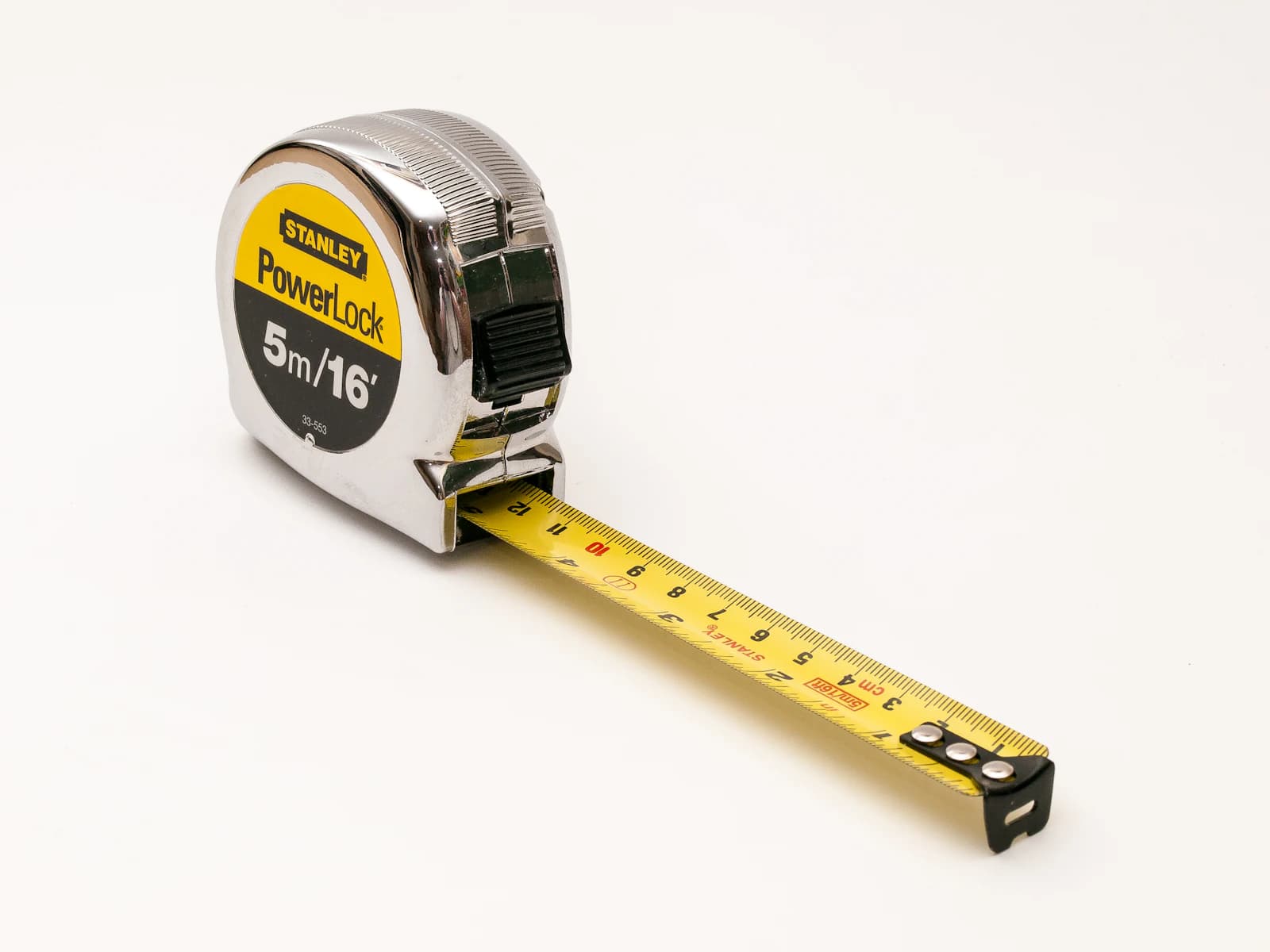 A tape measure and pencil laid on framing lumber while sizing out a deck