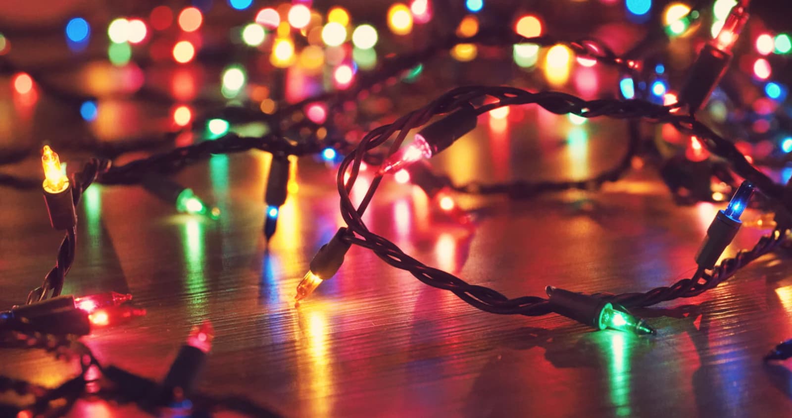 Warm string lights strung overhead above a deck seating area in the evening