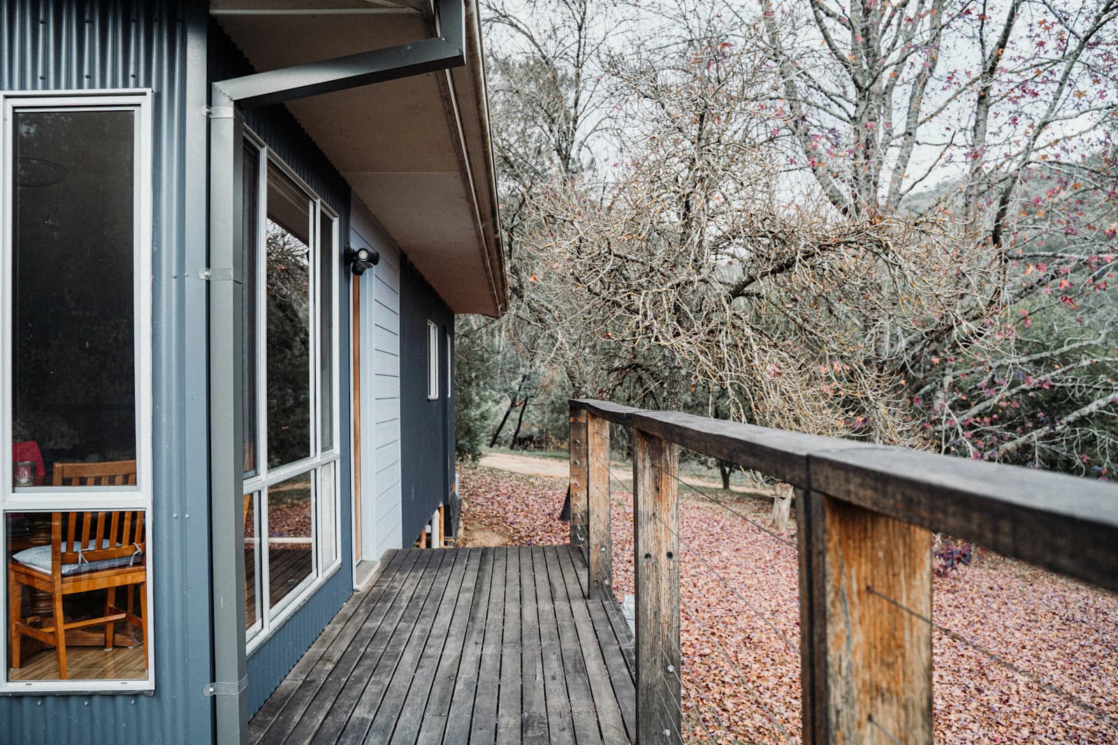The exterior of a home with a wooden deck furnished with a table and chairs