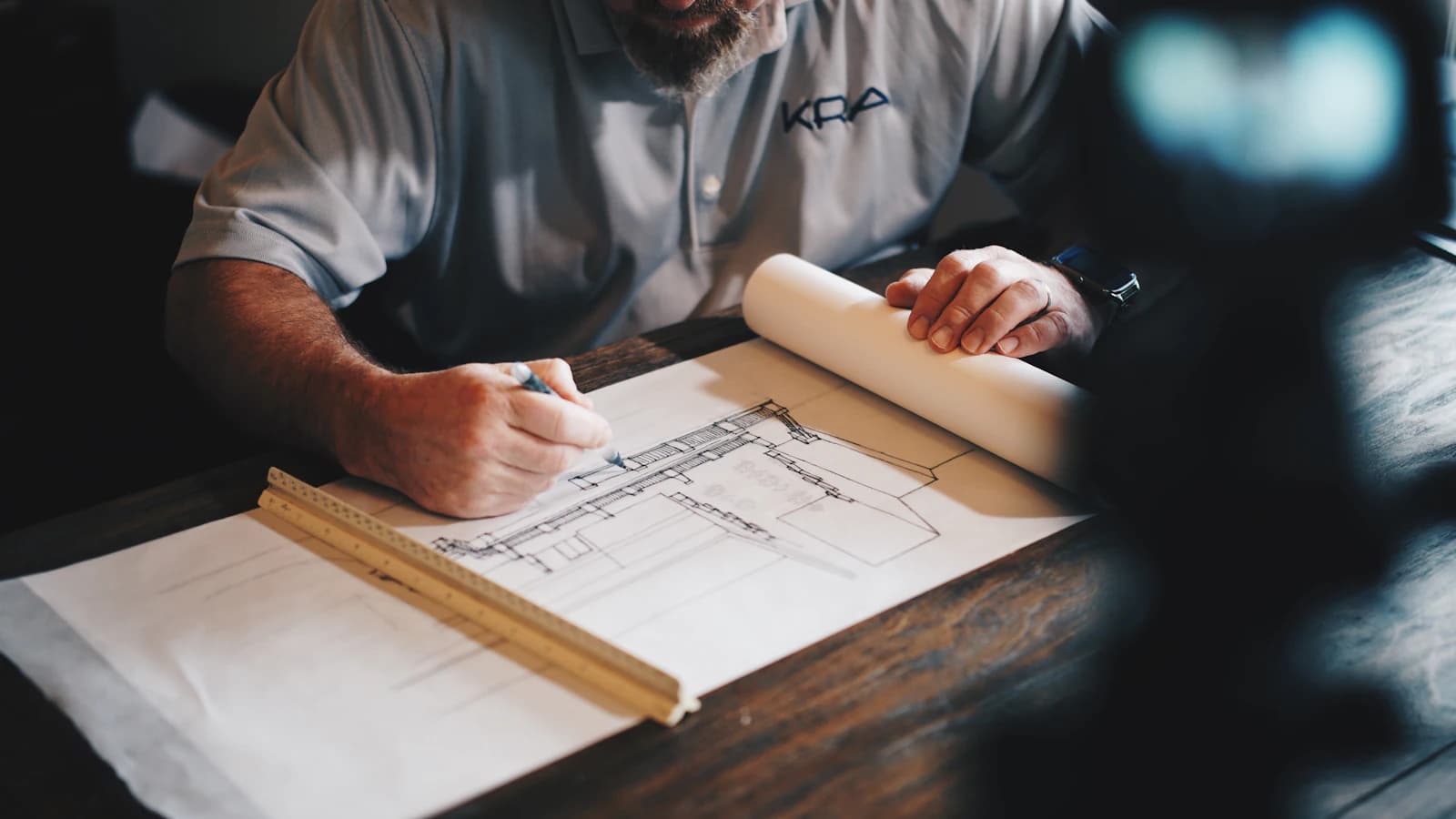 A person drafting building plans with a pencil and ruler