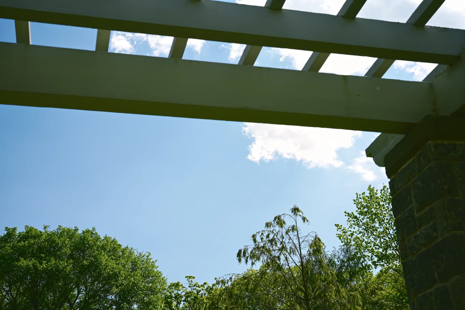 The underside of a solid patio roof structure attached to a home over an outdoor space