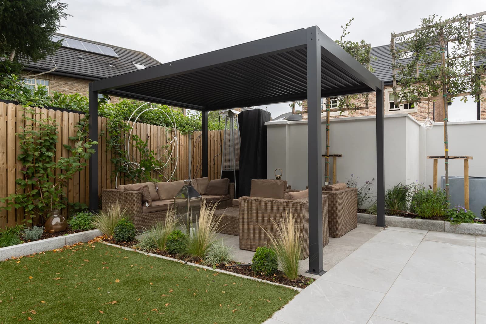 An open-slat wooden pergola casting dappled shade over a deck seating area