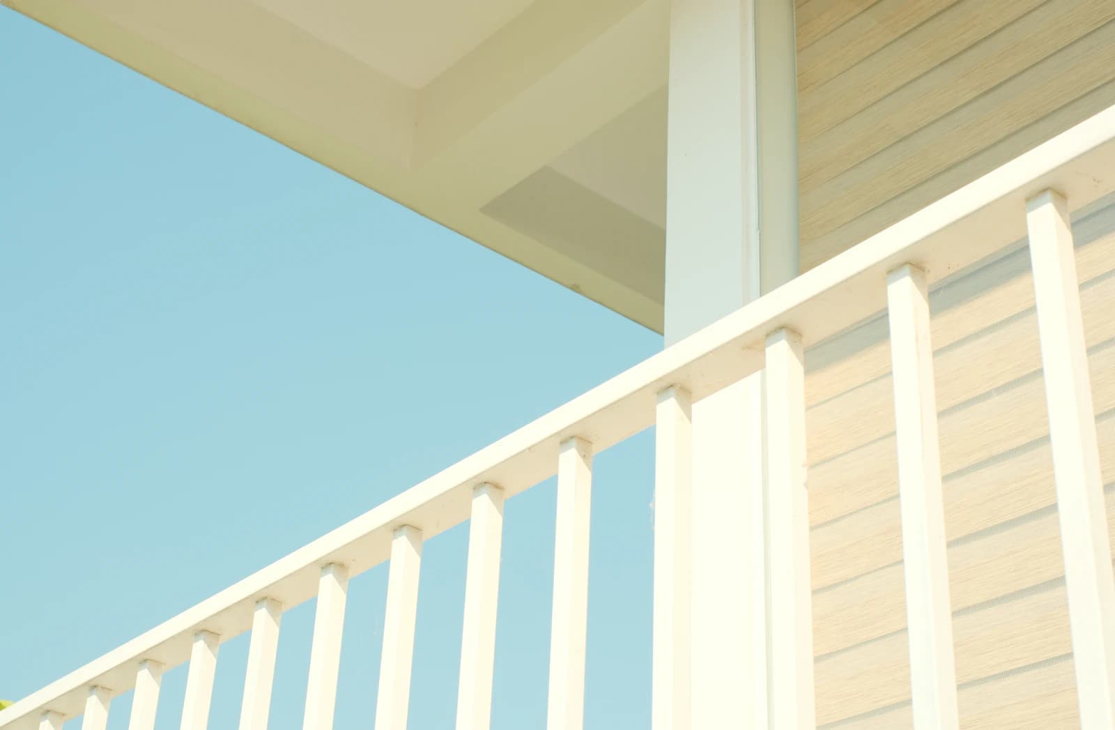 A bright white PVC deck railing standing against a clear blue sky