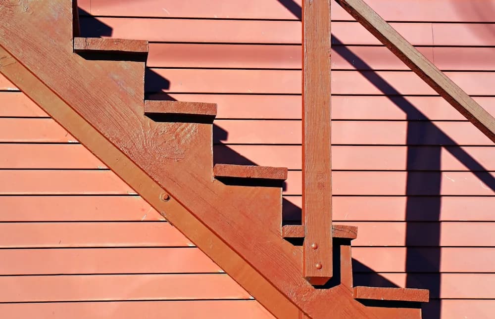 Wooden exterior staircase leading down from a raised deck